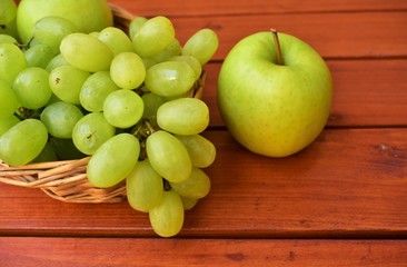 Green apple and bunch of grapes on a table.
