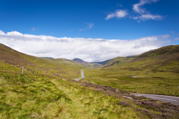 Narrow road along a valley in the Scottish Highlands in Scotland, United Kingdom; Concept for travel in Scotland