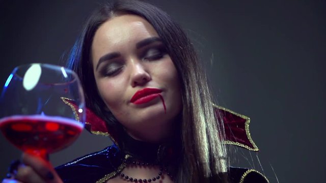 Halloween. Beauty sexy vampire woman drinking red wine. Slow motion. 4K UHD video 3840x2160