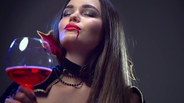 Halloween. Beauty sexy vampire woman drinking red wine. Slow motion. 4K UHD video 3840x2160