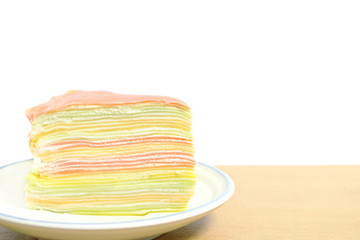piece of colorful crape cake dessert on white dish on wood table have copy space on white background