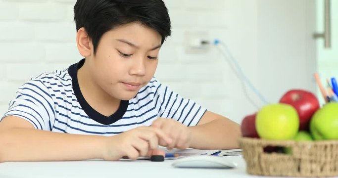 Cute asian boy doing homework at home with smile face.
