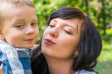 Mom hug and kiss their small son. Happy family - Mom and child- for a walk in the park.