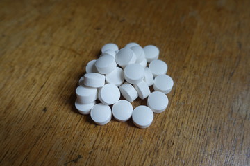 Fototapeta na wymiar Close view of handful of white pills on wood