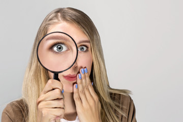 Curious woman looking through a magnifying glass