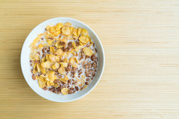 bowl of cereal with chocolate flaked rice on light wooden table background and copy space.
Cornflakes cereal and milk. Morning breakfast.