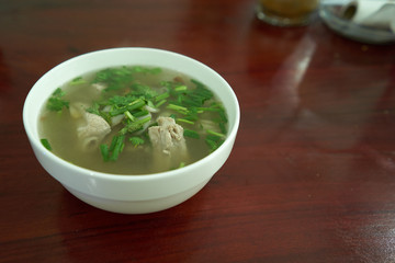 Boil the pork, garnish with coriander in white on a wood table.