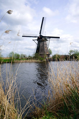 Dutch windmill in the afternoon build and standing next to polder water in kinderdijk south holland used to drain water out by using  wind power and keep land dry.