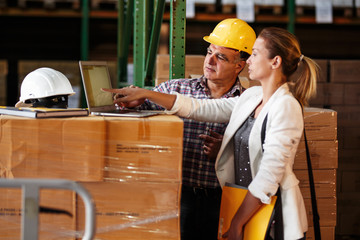 Female manager and warehouse worker checking list and inventory on laptop.Customs.