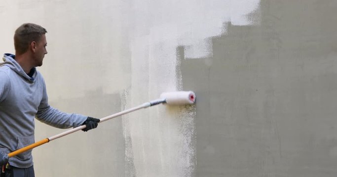 house painter painting building exterior with roller