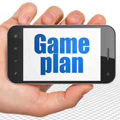 Finance concept: Hand Holding Smartphone with Game Plan on display