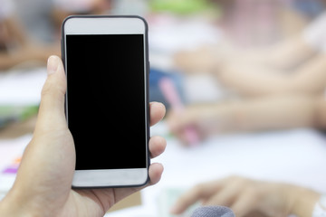 Hand holding smartphone with staff working