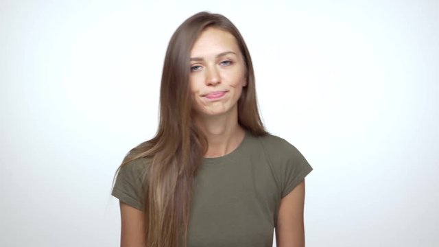 caucasian blue-eyed girl shrugging expressing hesitation with pursed lips over white background. Concept of emotions