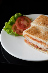 Close up healthy sandwich toast with lettuce, fried pork, cheese and tomato on a black marble background.