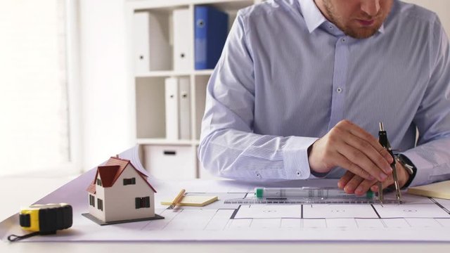 male architect with compass measuring blueprint