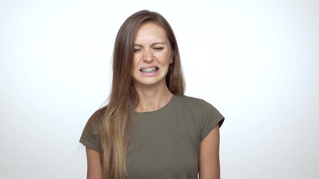 lady with long brown hair expressing disgust saying no with facial expresions over white background. Concept of emotions