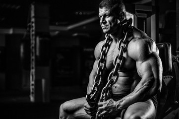 Fototapeta na wymiar Brutal bodybuilder working out in gym with chain.