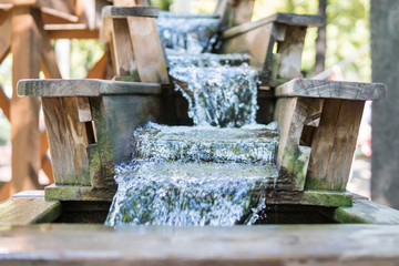 Fast stream flowing on a wooden trough, close-up