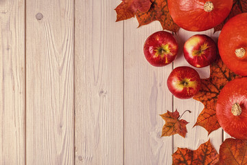 Autumn background with colored leaves and pumpkins on wooden background.