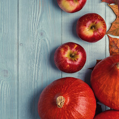 Autumn background with colored leaves and pumpkins on wooden background.