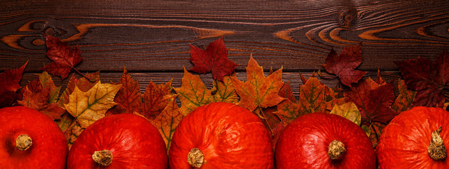 Naklejka na ściany i meble Autumn background with colored leaves and pumpkins on wooden background.
