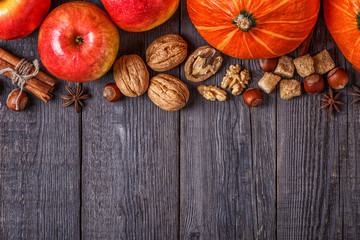 Wooden background with pumpkin, apples, nuts and spices.