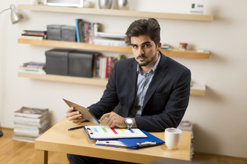Fototapeta premium Businessman analyzing investment charts on digital tablet at office