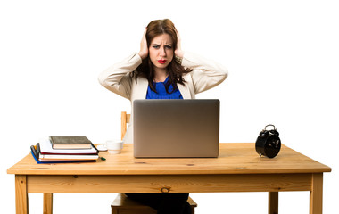 Business woman working with her laptop and covering her ears