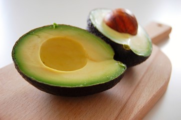 detail of fresh green avocado cut in pieces on wooden table - 174738332