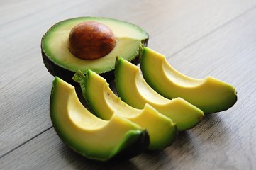 detail of fresh green avocado cut in pieces on wooden table - 174738341