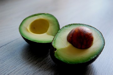 detail of fresh green avocado cut in pieces on wooden table - 174738342