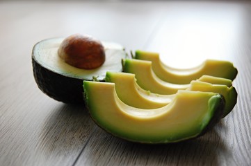 detail of fresh green avocado cut in pieces on wooden table - 174738355