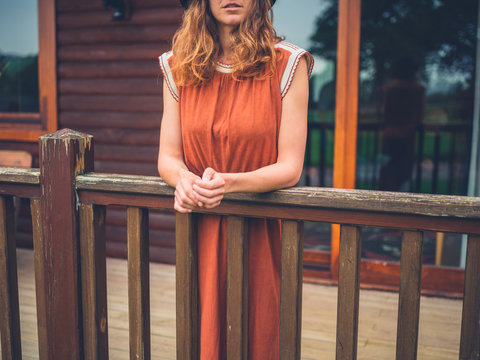 Woman in dress standing on porch of cabin