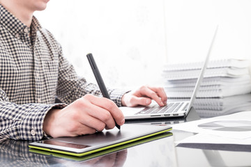 Designer working with graphics tablet and laptop in office