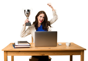 Business woman working with her laptop and holding a trophy