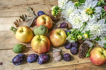 Green nuts,prunes,apples and figs with a bouquet of  white dahlias on wooden boards

