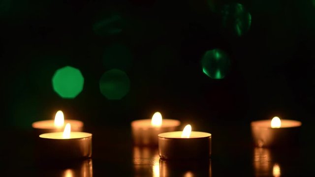 candles on table in dark, against background of multicolored luminous bokeh