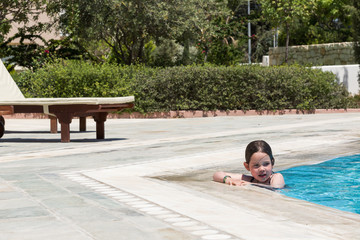 Obraz na płótnie Canvas Happy little girl swimming in a pool