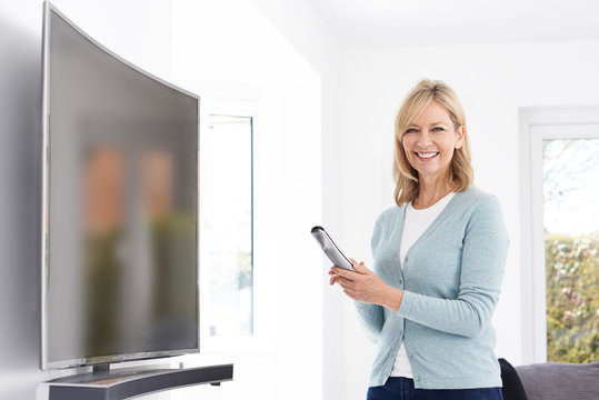 Mature Woman With New Curved Screen Television At Home