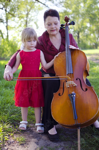 Old Women And Blond Caucasian Girl Playing Concert On Cello