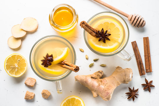 Hot Ginger tea with lemon, honey and spices. Top view on white table.