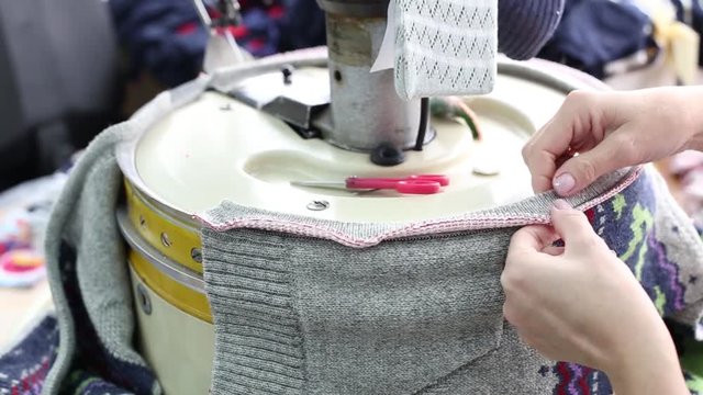 Close up of woman hands sewing an overlock at sewing machine. Automatic sewing machine. Tailor woman. Overlock stitch on sewing machine.