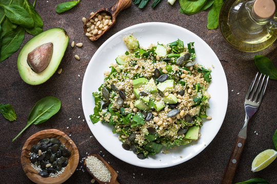Fresh quinoa salad with spinach, avocado, seeds and Pine nuts. Top view on dark table.