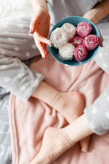 Young woman holds teal plate with zephyrs in hands. Delicious confectionery and homemade gourmet cookies start from the morning, top view. Broken diet, temptation, unhealthy food concept