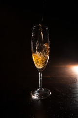 Champagne splash in motion on black background. Alcohol advertising closeup, exquisite beverage pouring in champagne flute. Tasty alcoholic drink, commercial concept