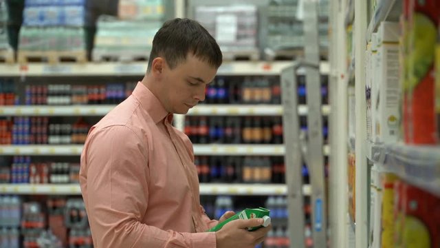 young guy buys juice in a store or supermarket.