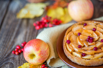 Apple pie on a wooden texture with red berries
