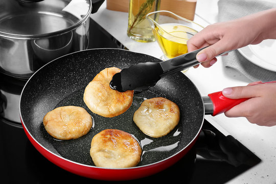 Woman frying pancakes in kitchen