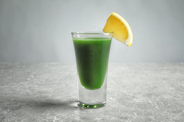 Wheat grass shot served with lemon on grey table