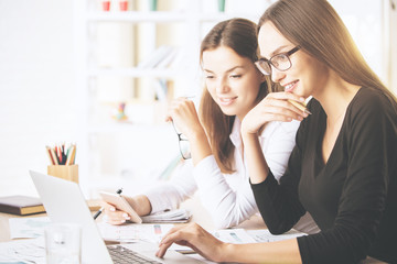 Attractive girls using laptop at workplace